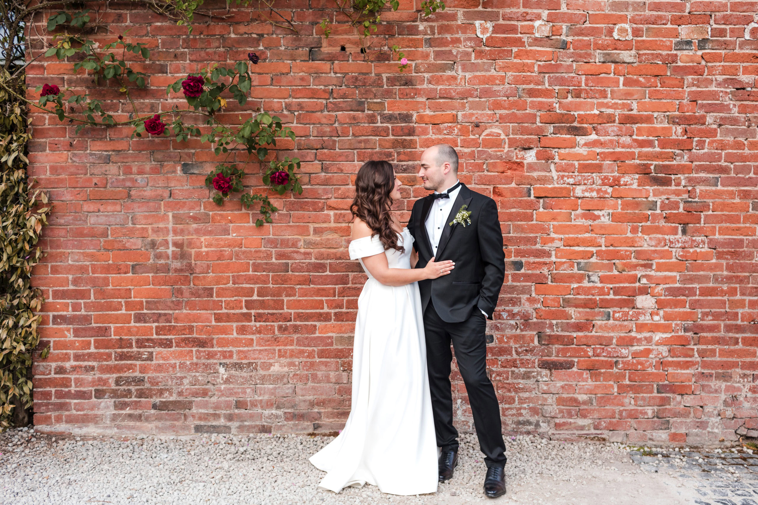 couple standing in front of a rustic brick wall at their St Johns House wedding