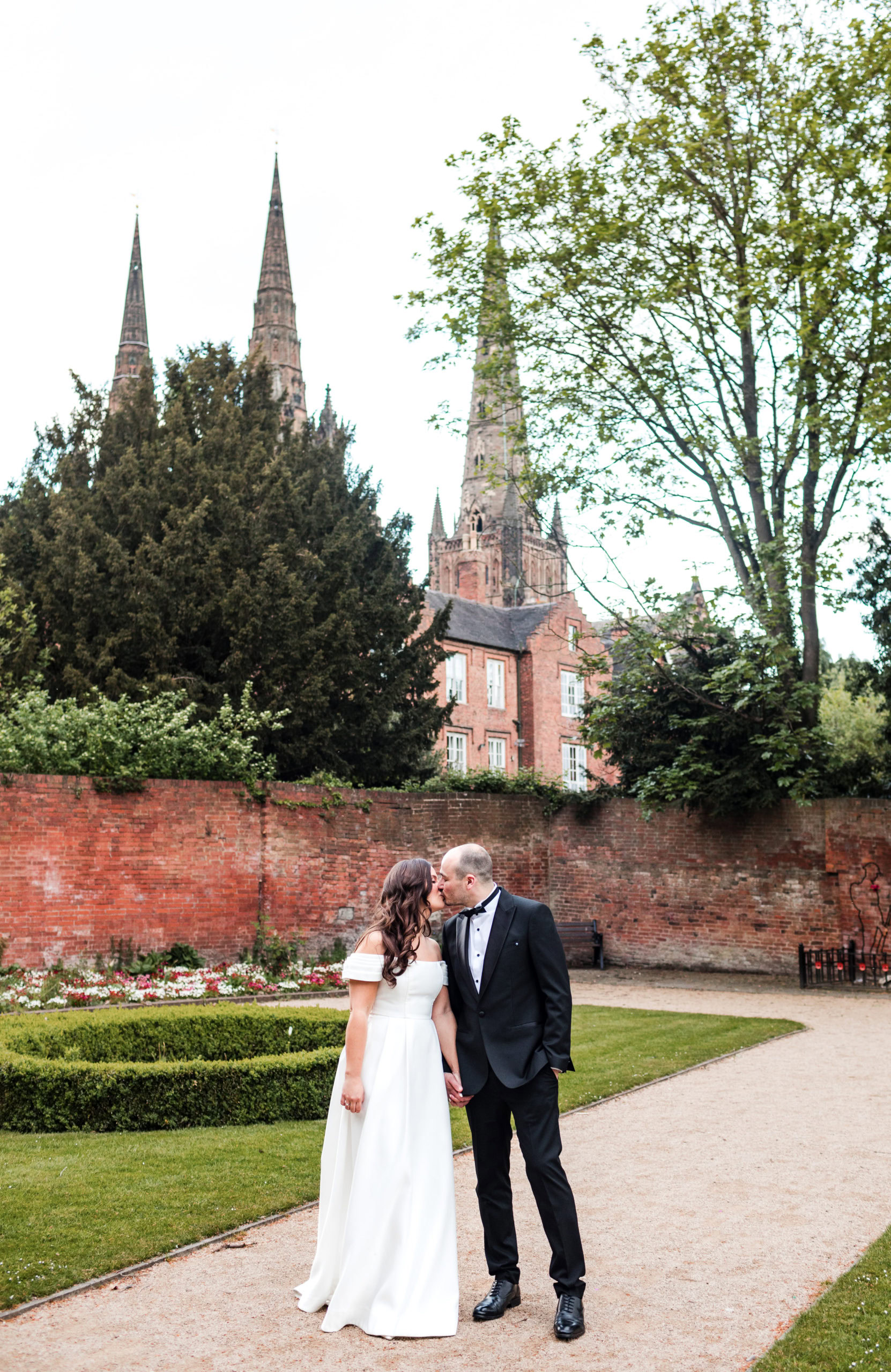 Bride and Groom share a kiss in the Memorial Garden with Lichfield Cathedral behind them